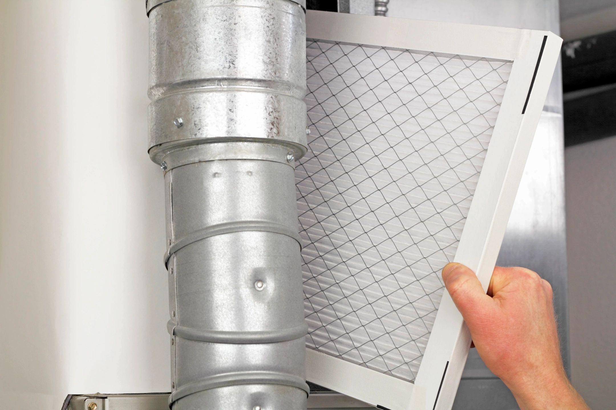 Person replacing an HVAC air filter in a Hampton, VA home as part of fall seasonal maintenance.